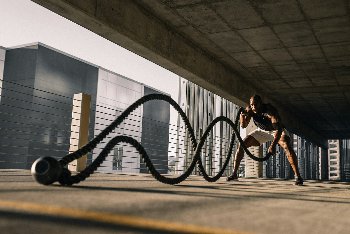Athlete training outdoors with battle ropes, versatile fitness lifestyle
